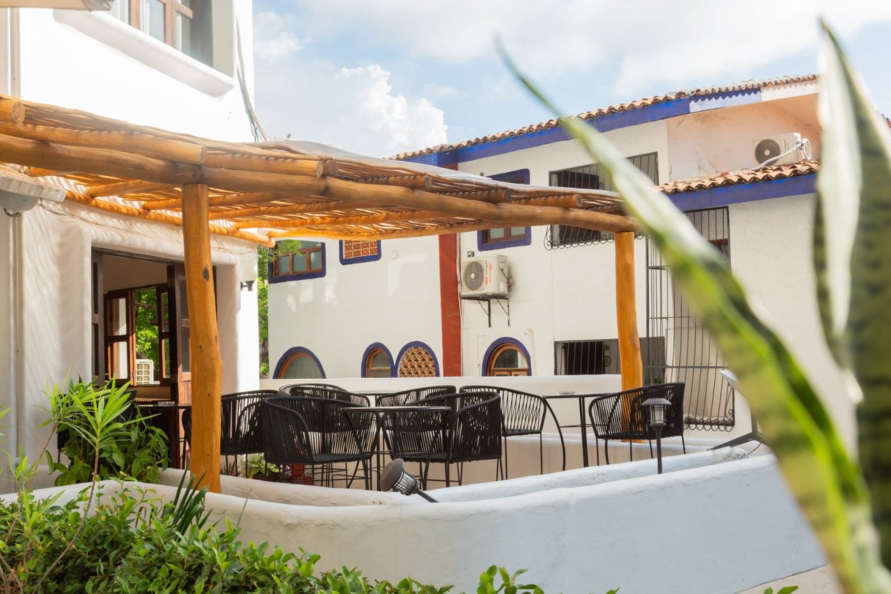 Tables on the first-floor terrace under the wooden pergola, set for breakfast