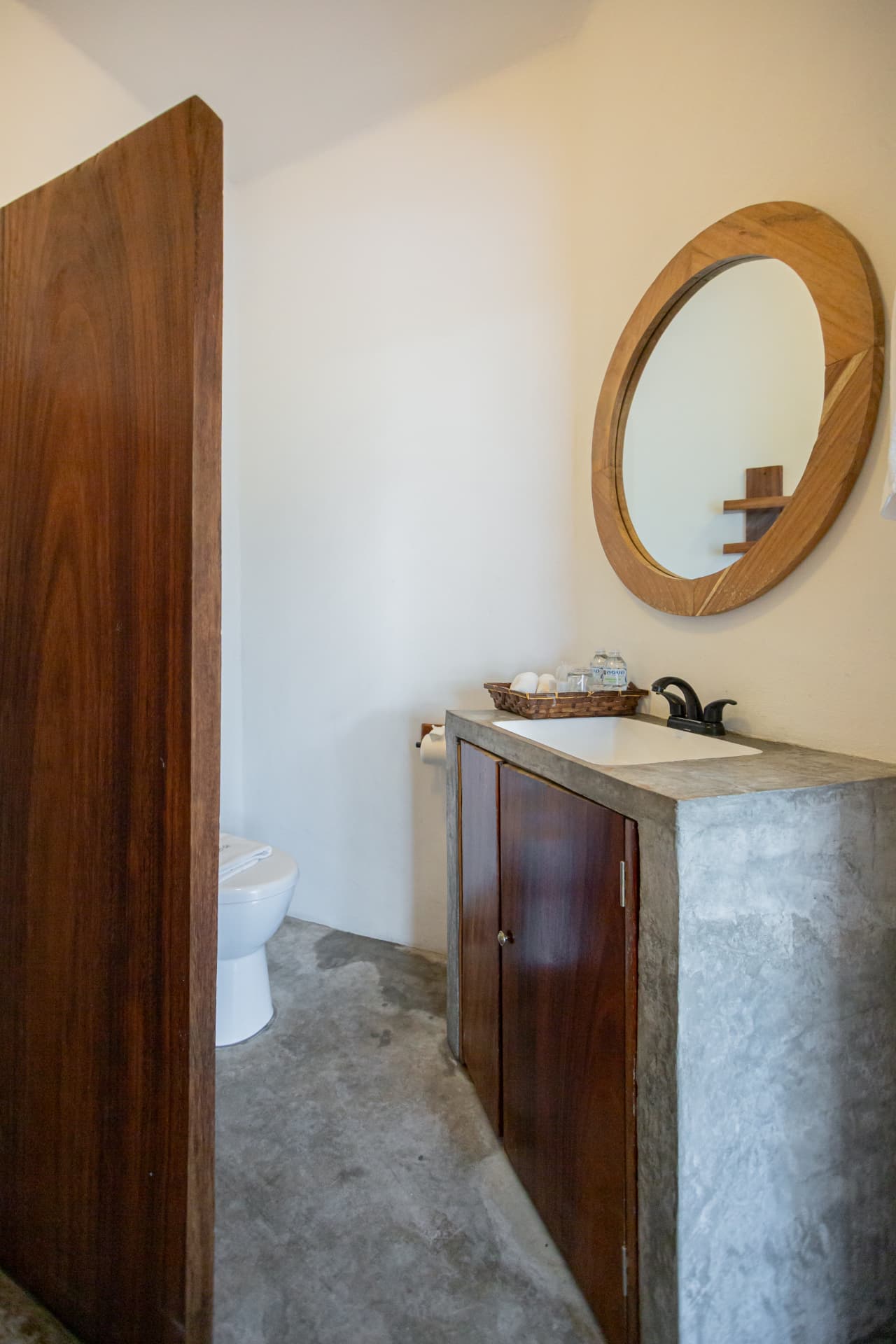 Lavabo de concreto con espejo redondo de madera en la habitación 206