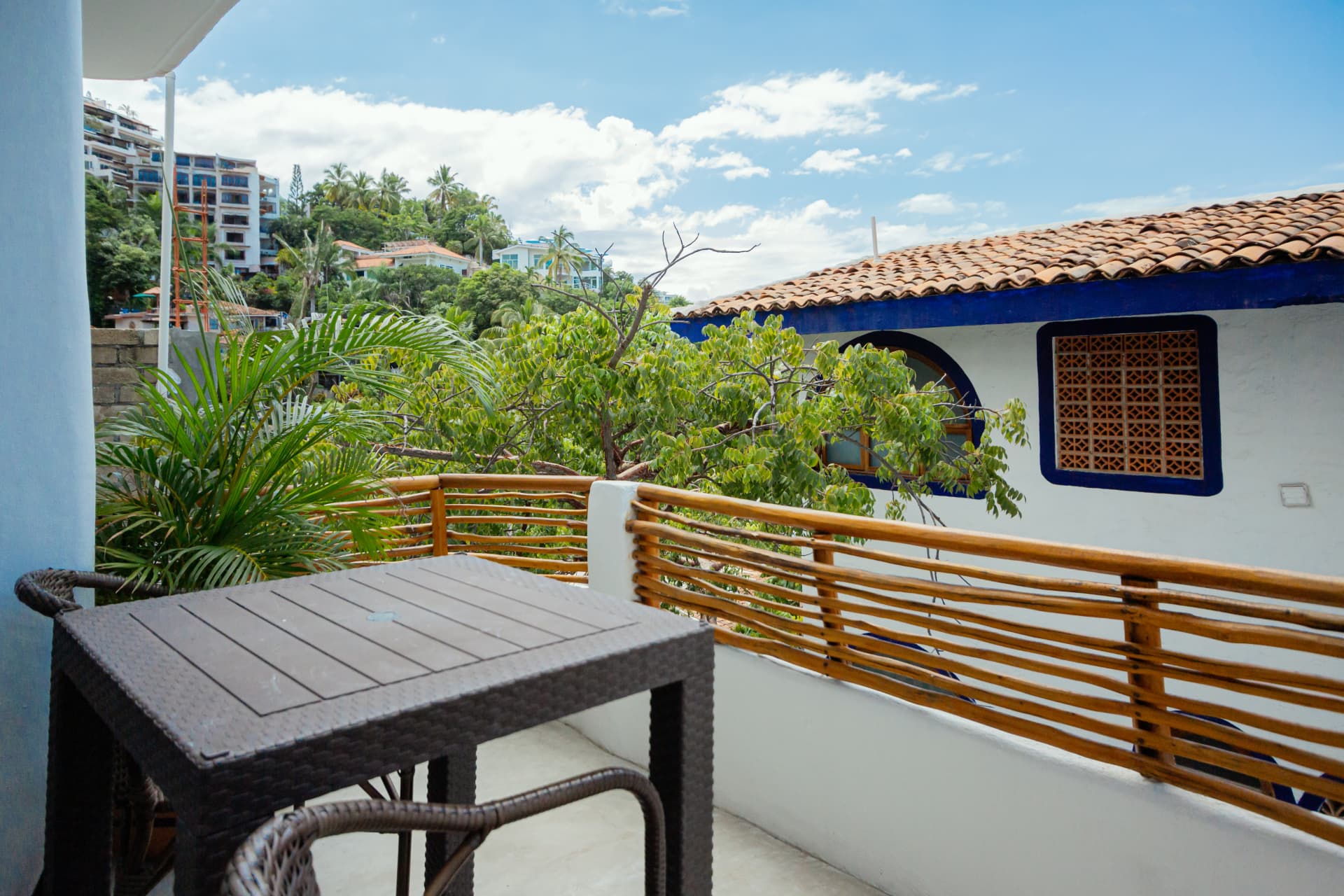 Balcony of Room 202 with rattan table and views of white rooftops and the hillside