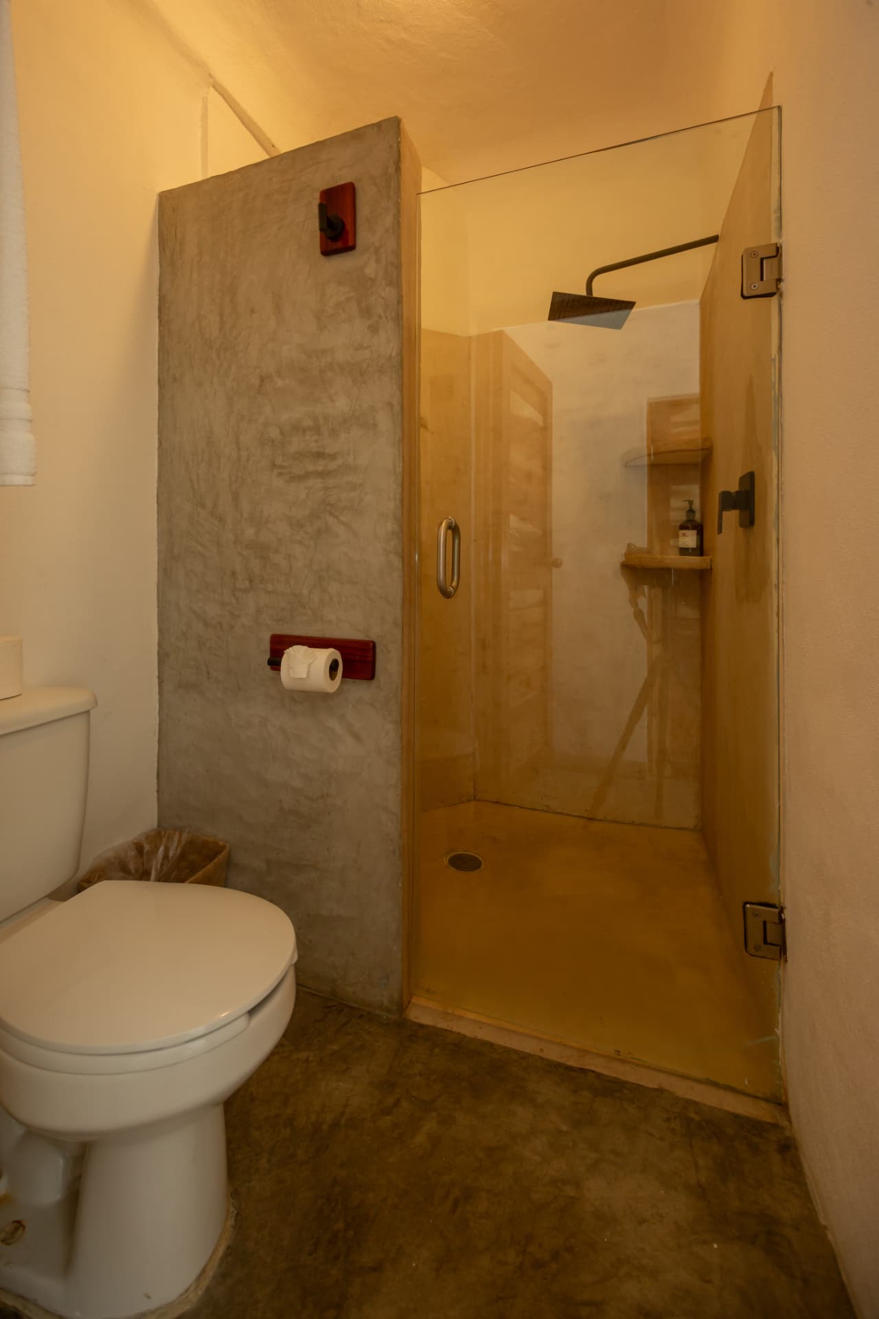Bathroom in room 105 with glass shower and concrete wall