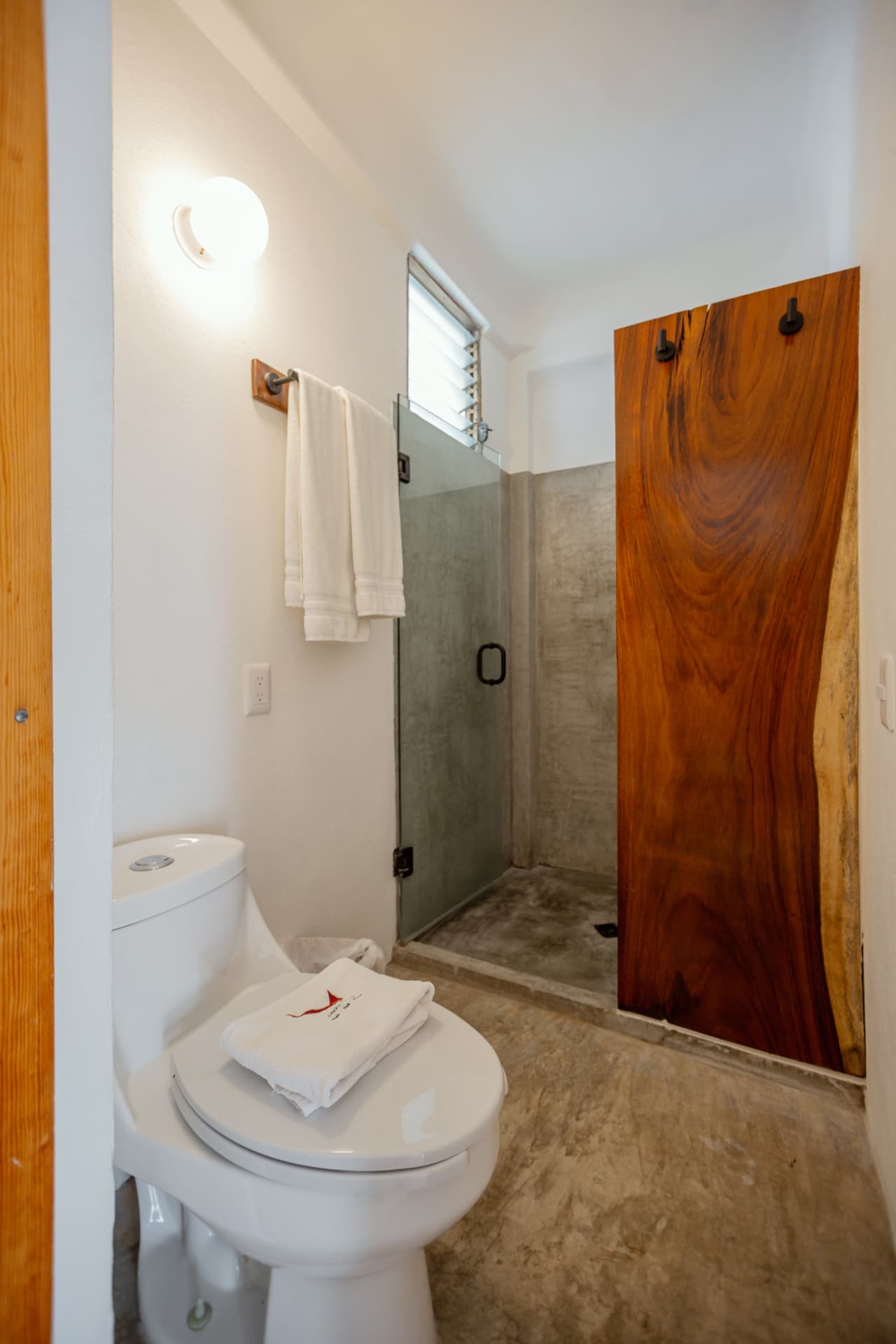 Regadera de concreto con puerta de madera en el baño de la Premium King 305