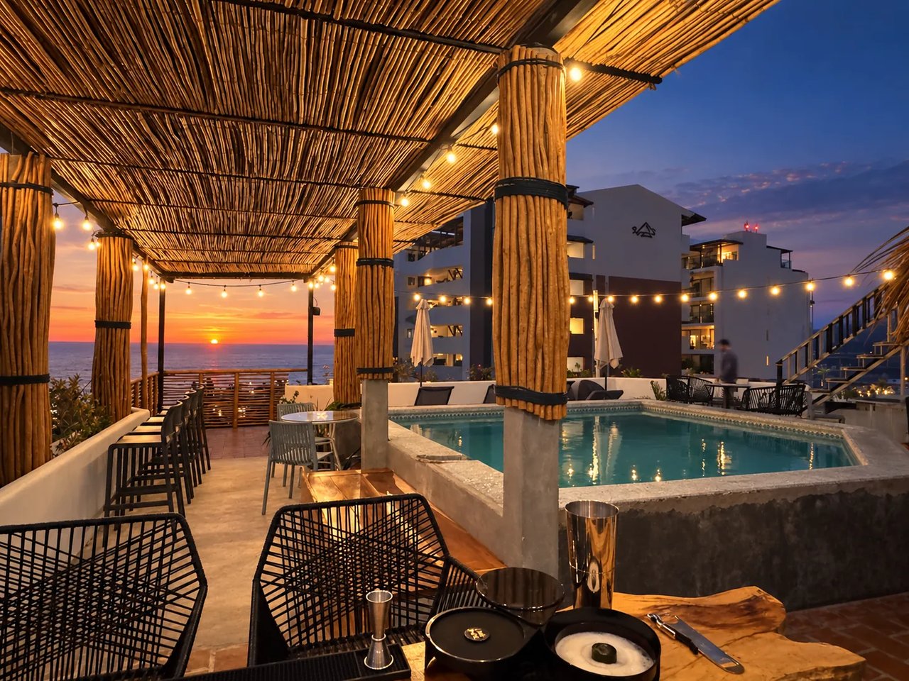 Pergola palapa avec lumières au-dessus de la piscine au coucher du soleil