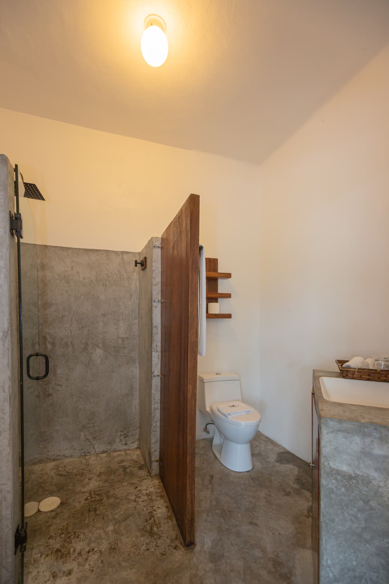 Baño de la habitación 206 con regadera de concreto y puerta de madera