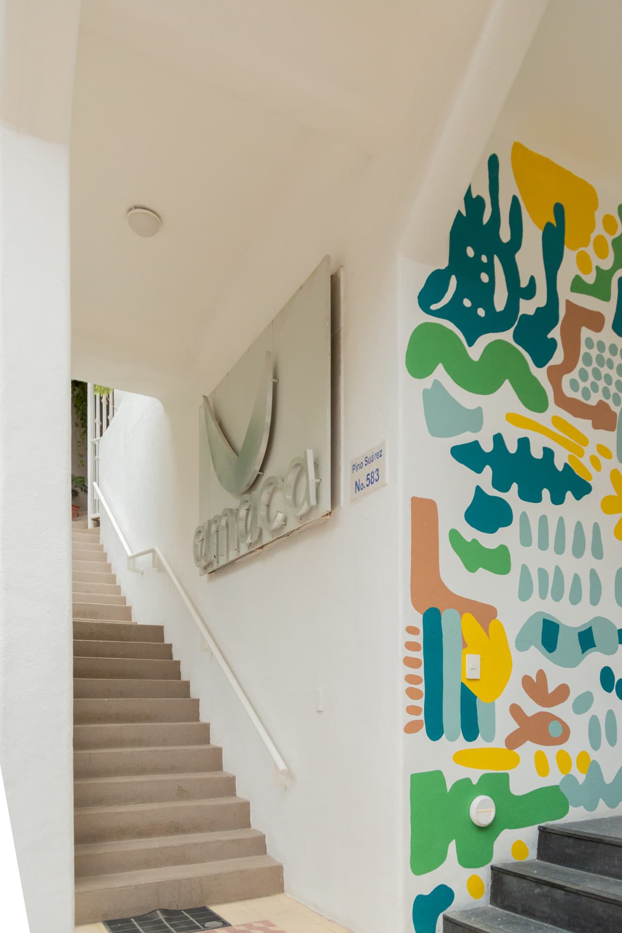 Access to Amaca Residence next to the colorful mural and the hotel stairs