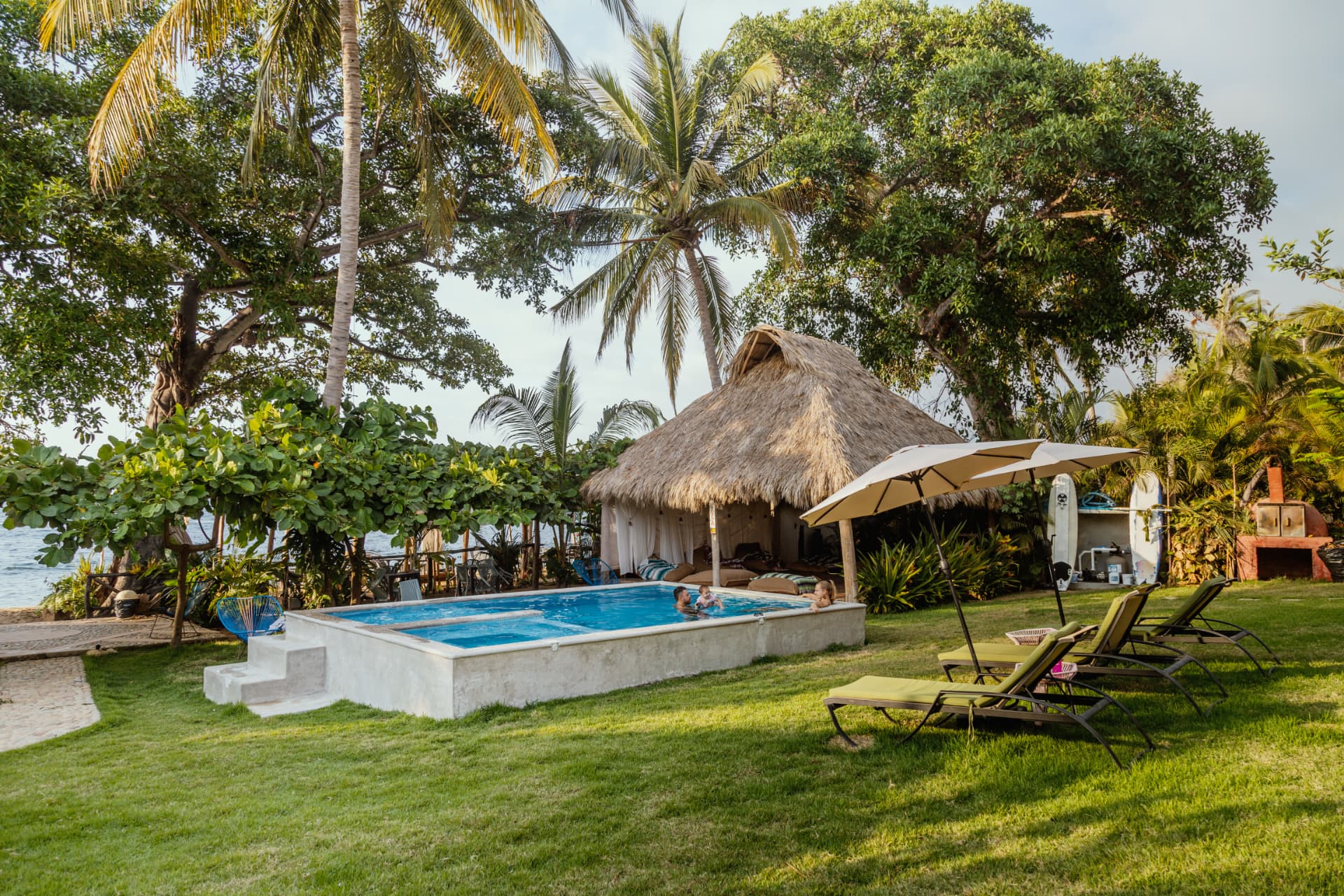Alberca, jardín tropical y palapa frente al mar en Amaca Beach Retreat