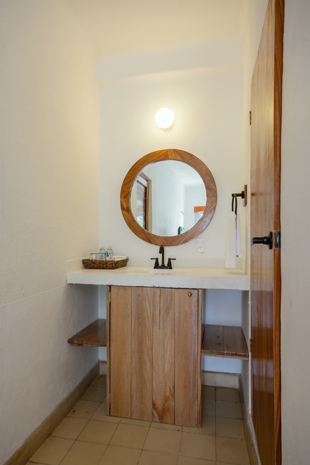 Lavabo con espejo redondo de madera en la habitación 205