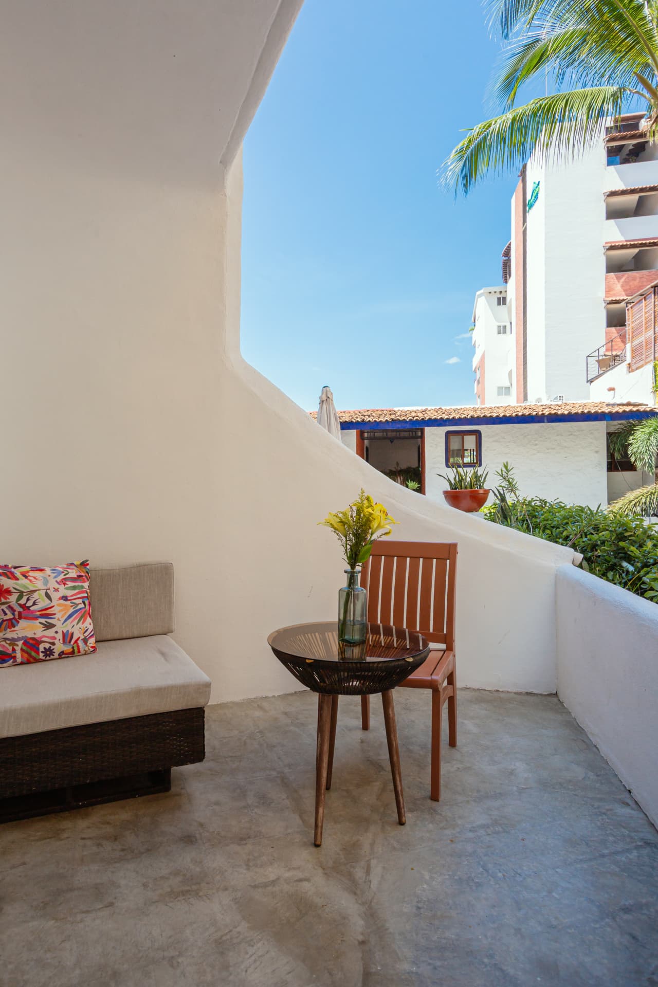 Balcón de la habitación 106 con mesa, silla y vista al barrio