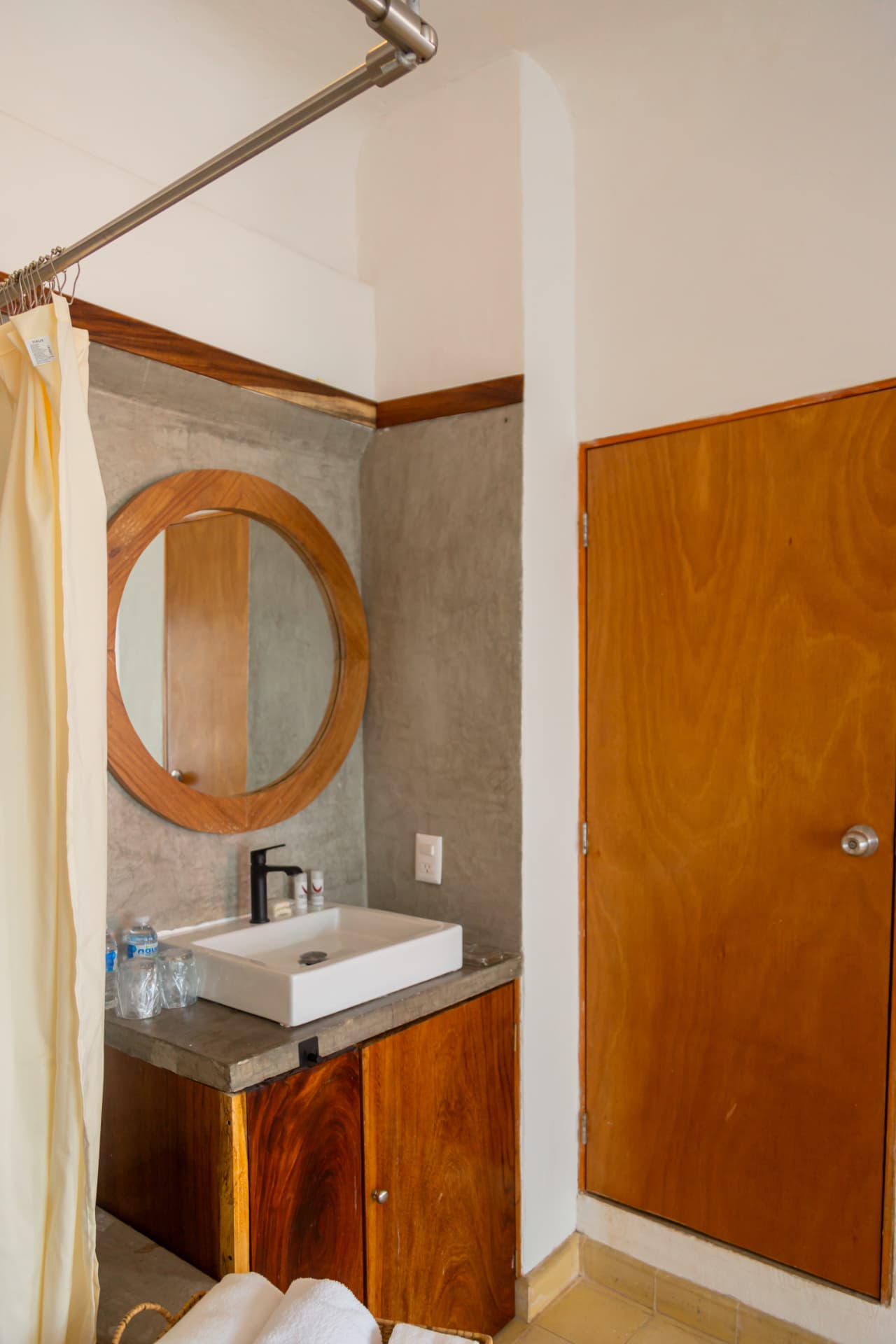 Bathroom of Amaca Residence with sink, round mirror and wooden furniture