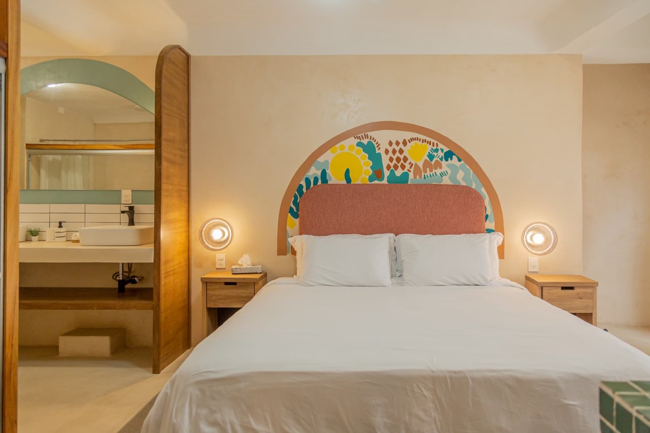 King bed of Amaca Residence with pink headboard and handcrafted mural