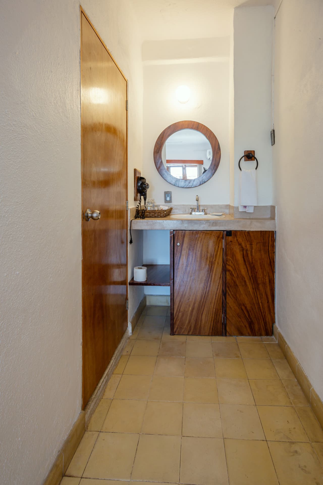 Lavabo de la habitación 204 con espejo redondo y mueble de madera