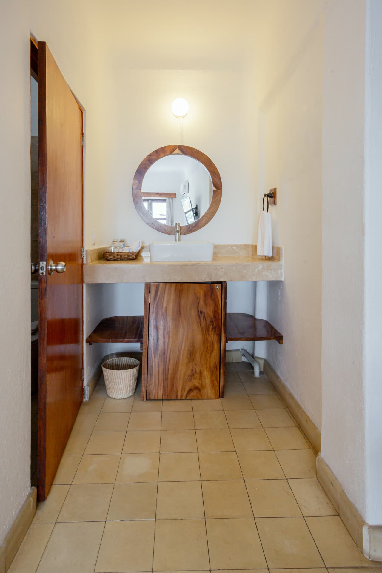 Lavabo de la habitación 304 con espejo redondo y mueble de madera