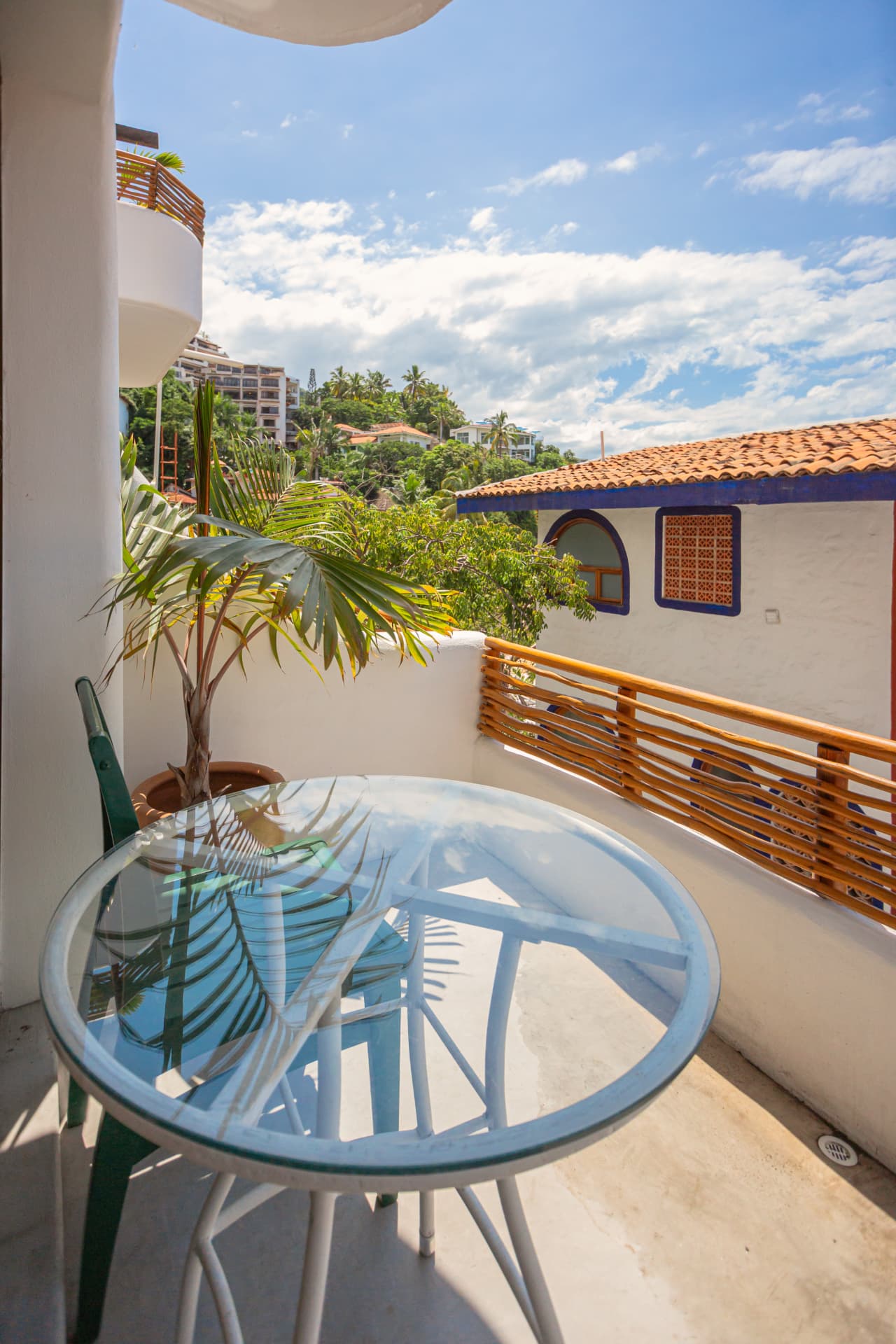 Balcón de la habitación 203: mesa de vidrio con vista a los techos de teja