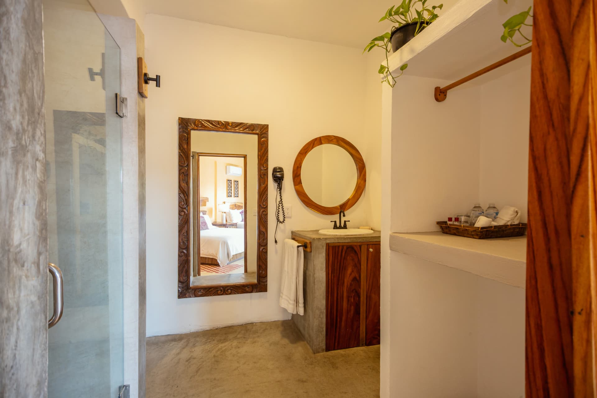 Habitación 203: vestidor con closet abierto, lavabo de concreto y espejo redondo