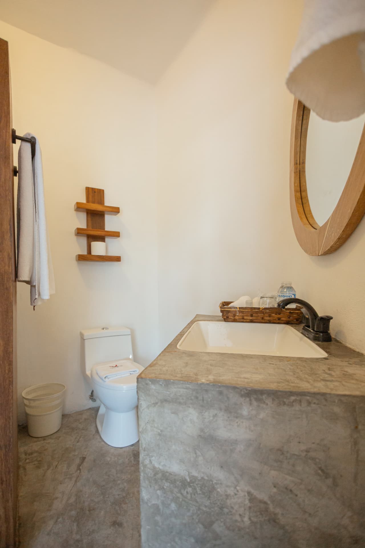 Detalle del lavabo con espejo redondo y estante de madera