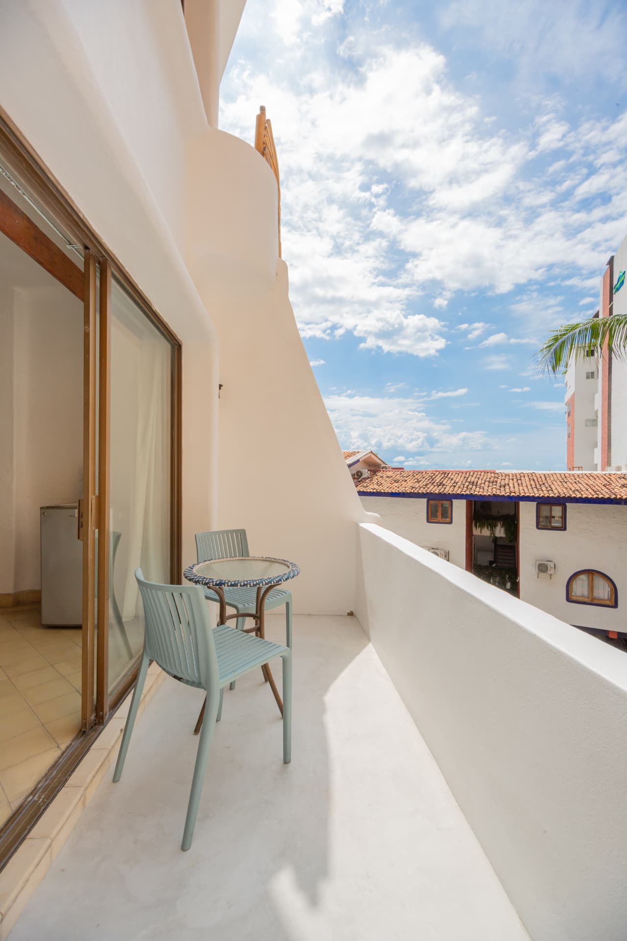 Balcón de la habitación 206 con mesa, sillas y vista a las palmeras del barrio