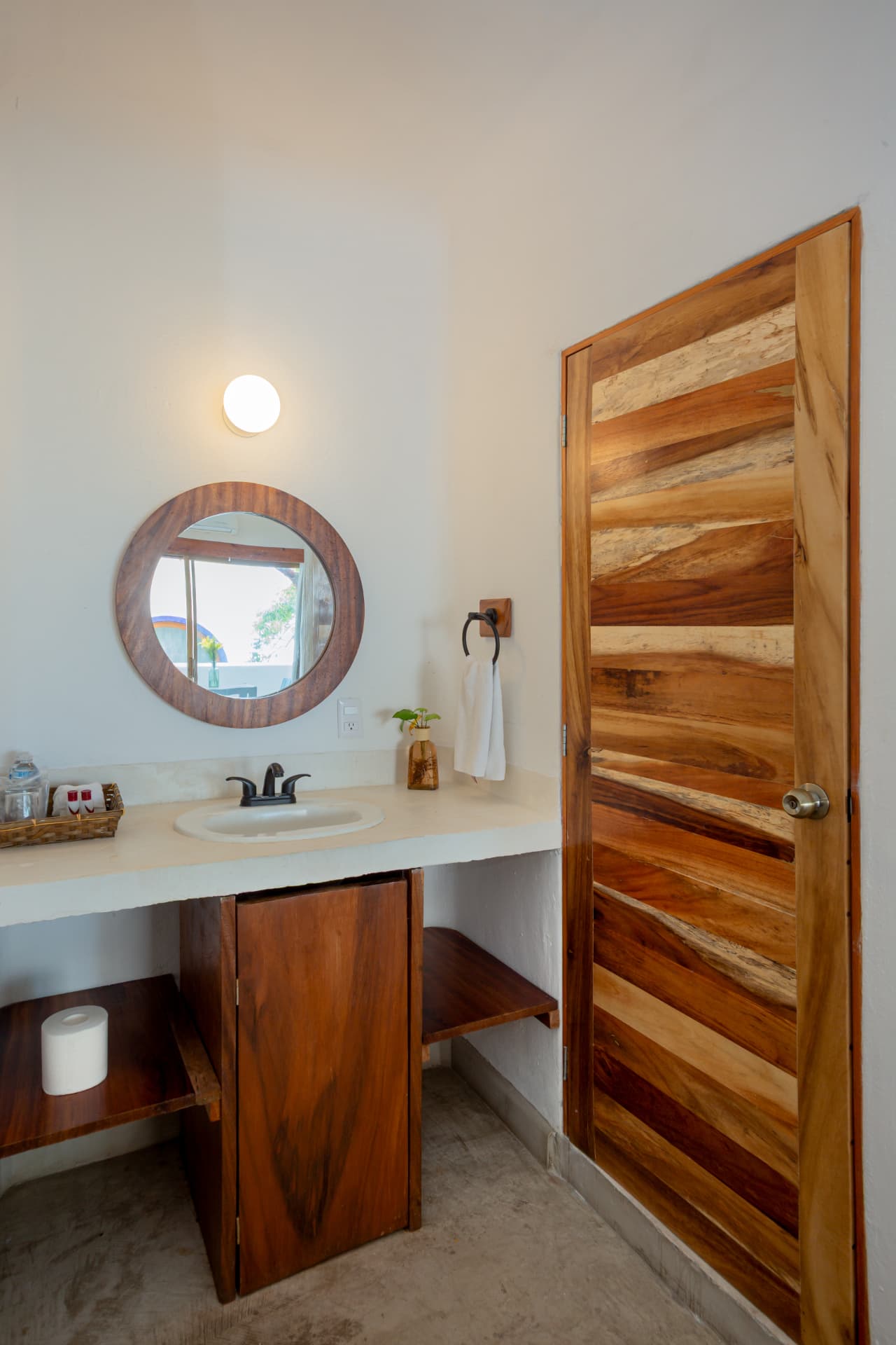 Lavabo de concreto con espejo redondo de madera