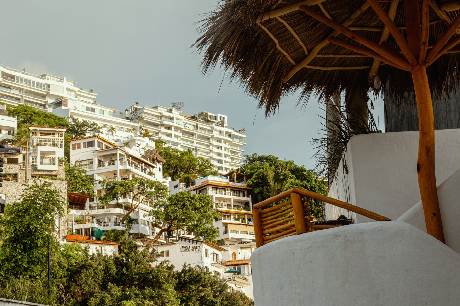 Palapa y muros curvos de Amaca frente a la ladera de Puerto Vallarta