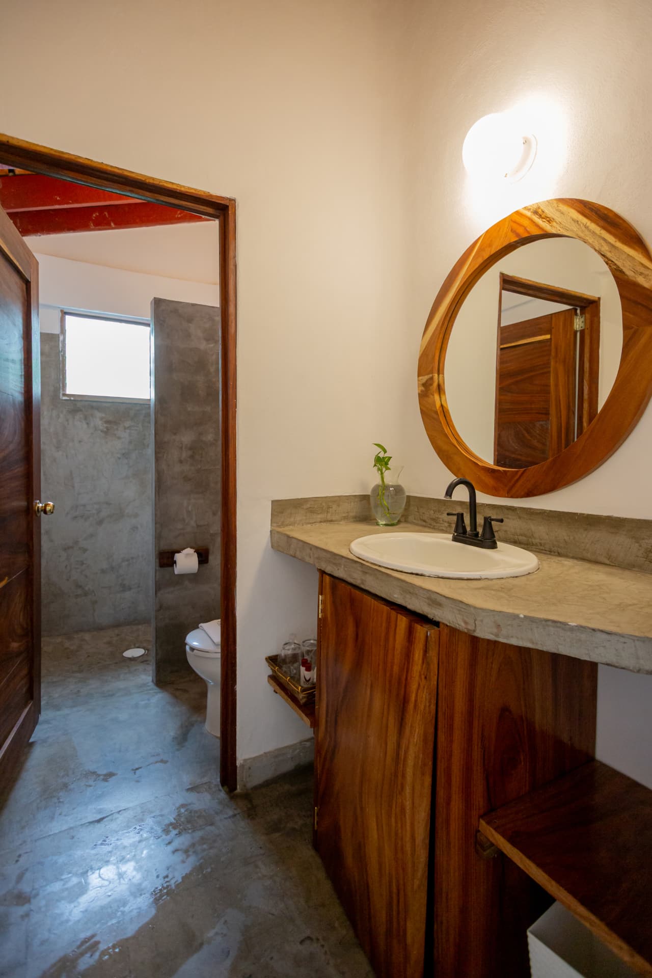 Lavabo de concreto con espejo redondo de madera en la habitación 307