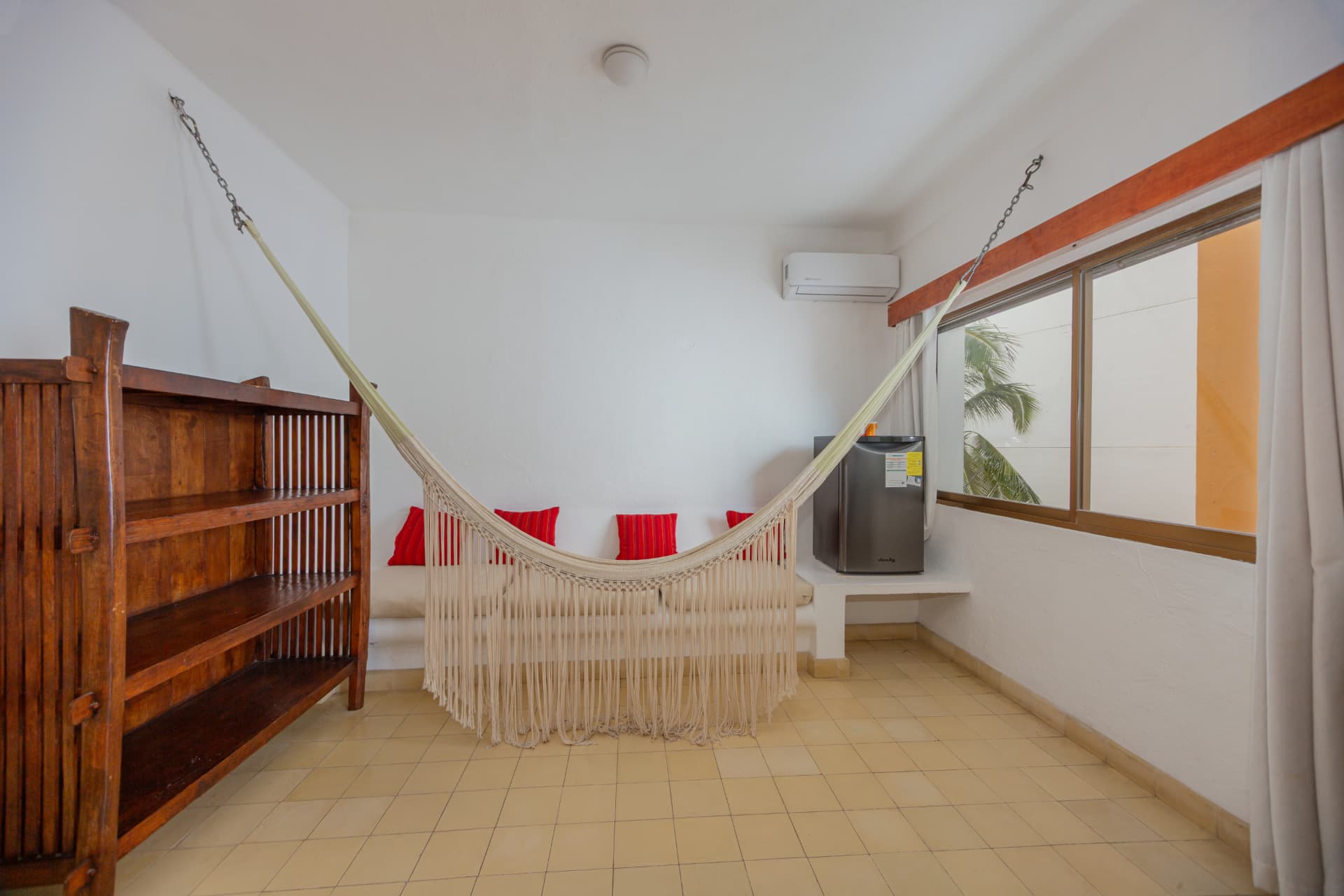 Hamaca con cojines rojos y minibar de la habitación 207