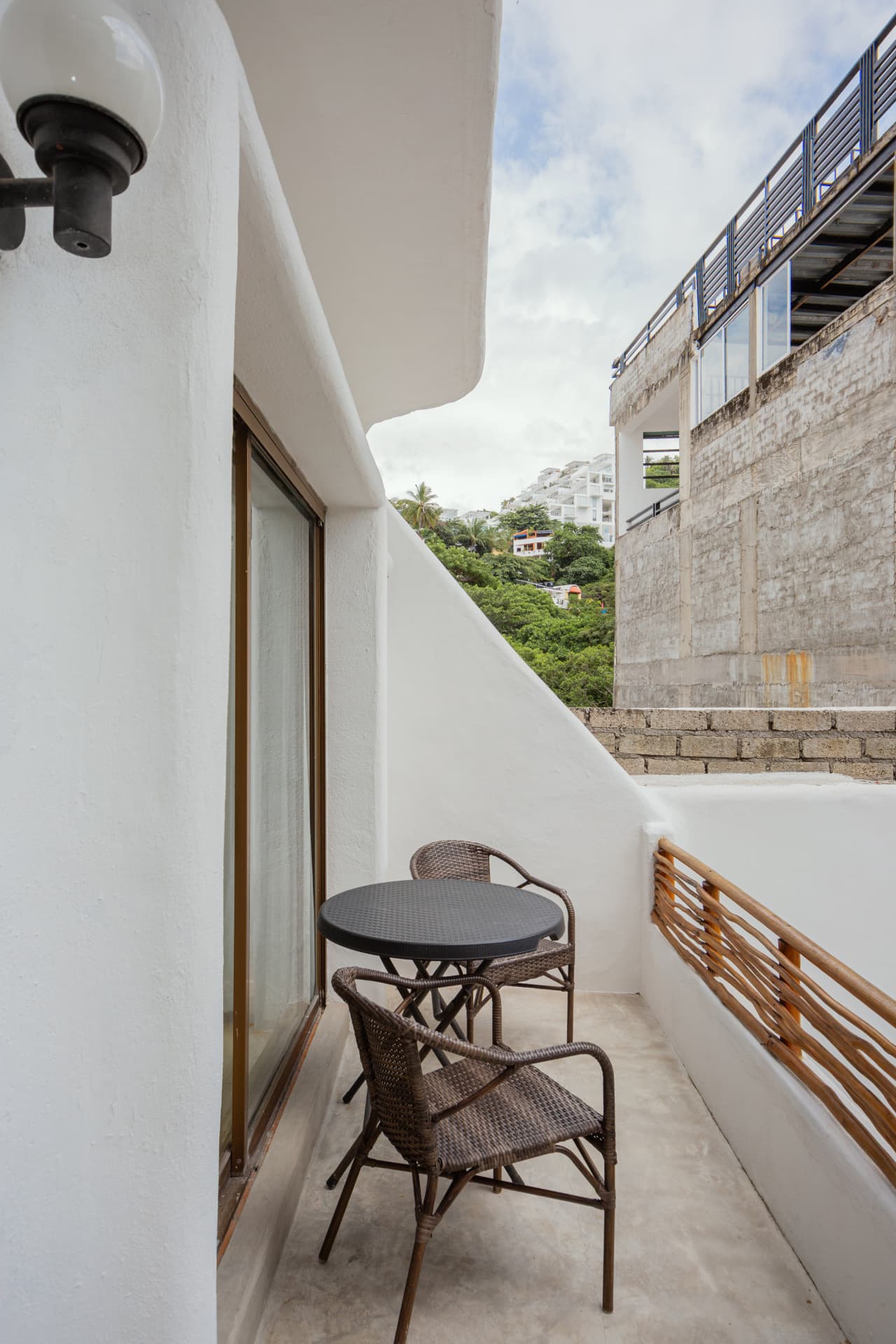 Balcón de la habitación 208 con mesa de hierro y sillas de rattan