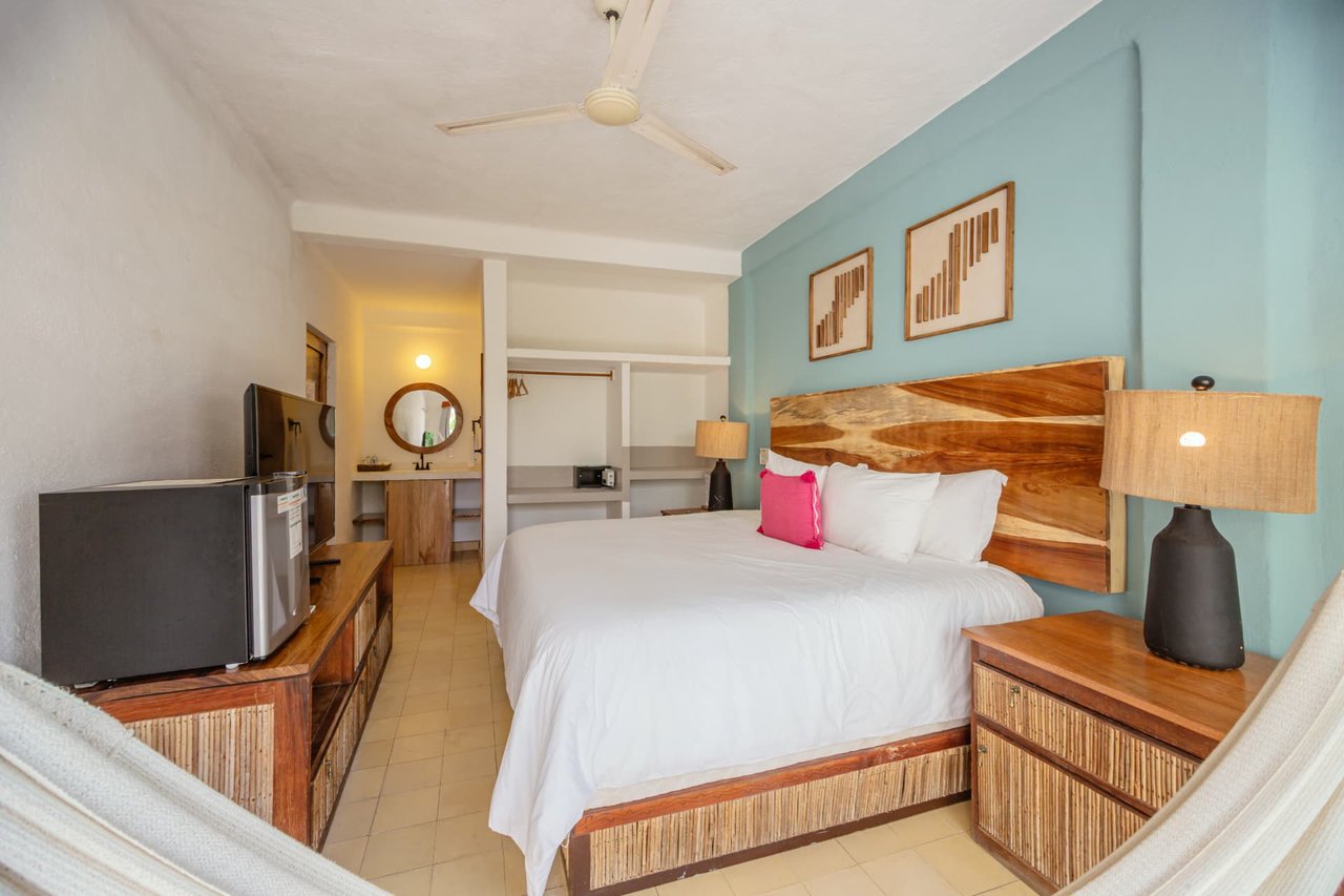 Queen bed in room 205 with wood headboard and blue wall
