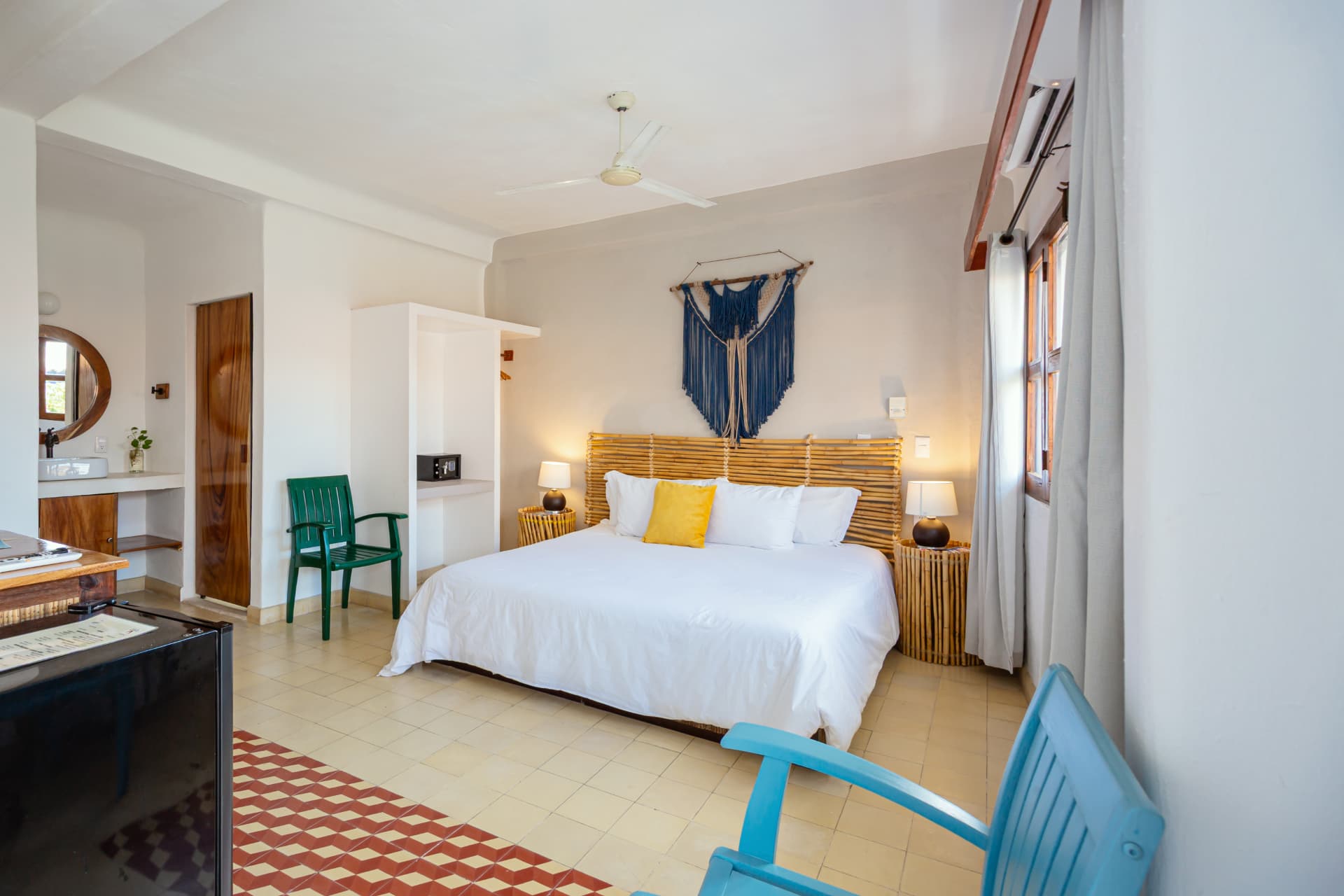 Bed in Room 202 with bamboo headboard, blue macrame and green and blue chairs