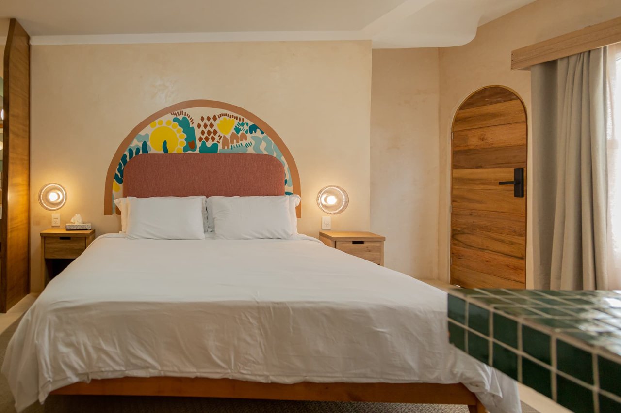 Main King bedroom of Amaca Residence with mural, pink headboard and curved door