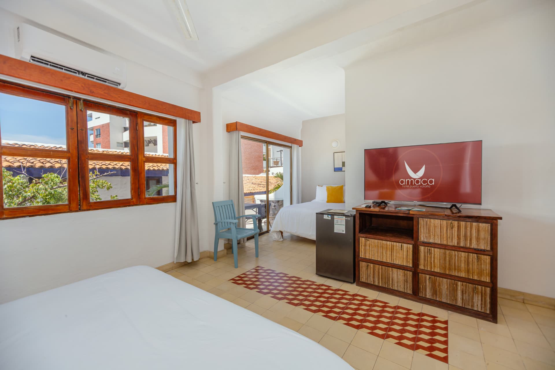 Habitación 202: vista hacia el balcón con silla azul y cama