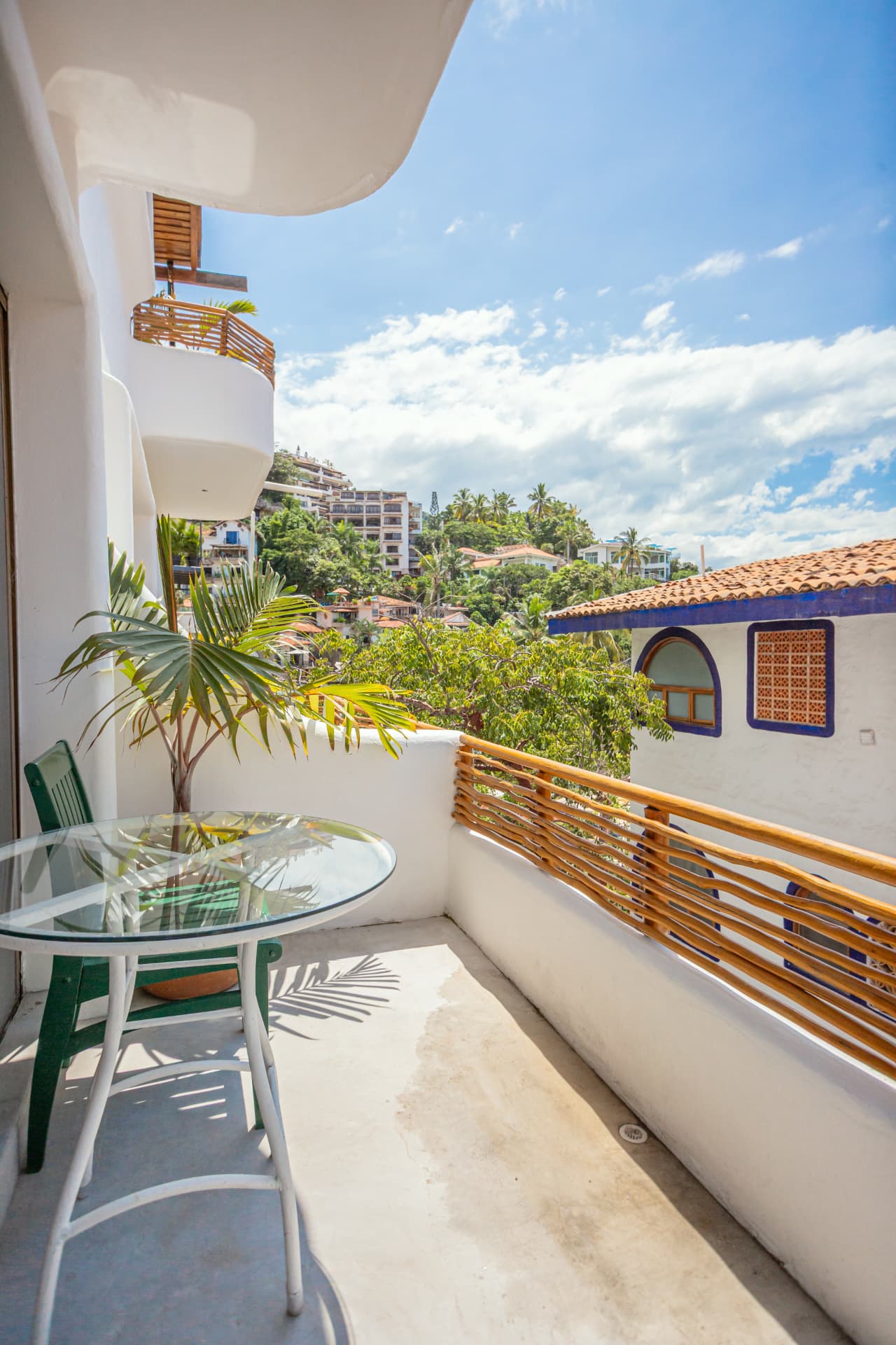 Balcón de la habitación 203: mesa de vidrio junto al barandal con vista a la vegetación