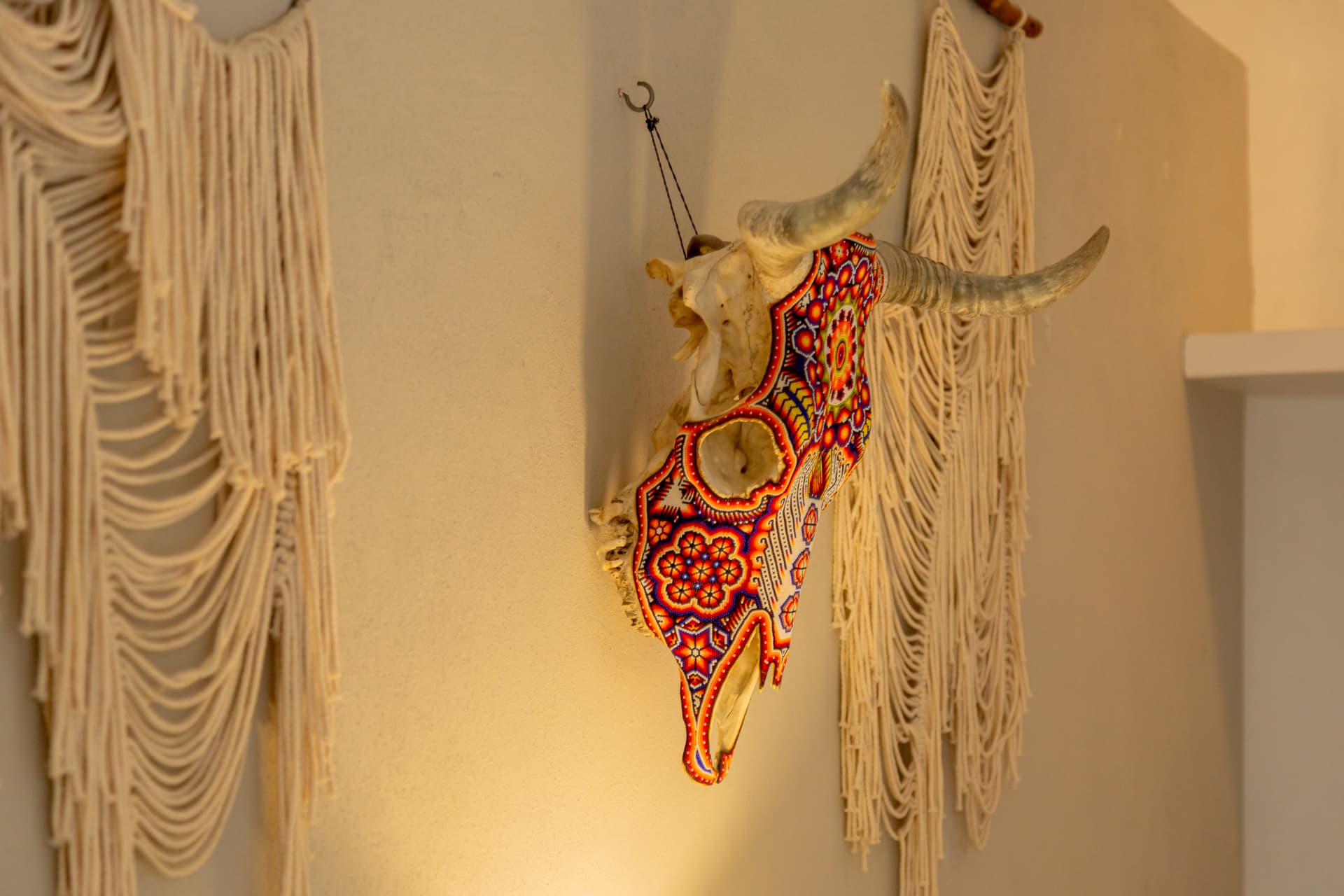 Cráneo decorado con arte Huichol entre macramés en la habitación 107