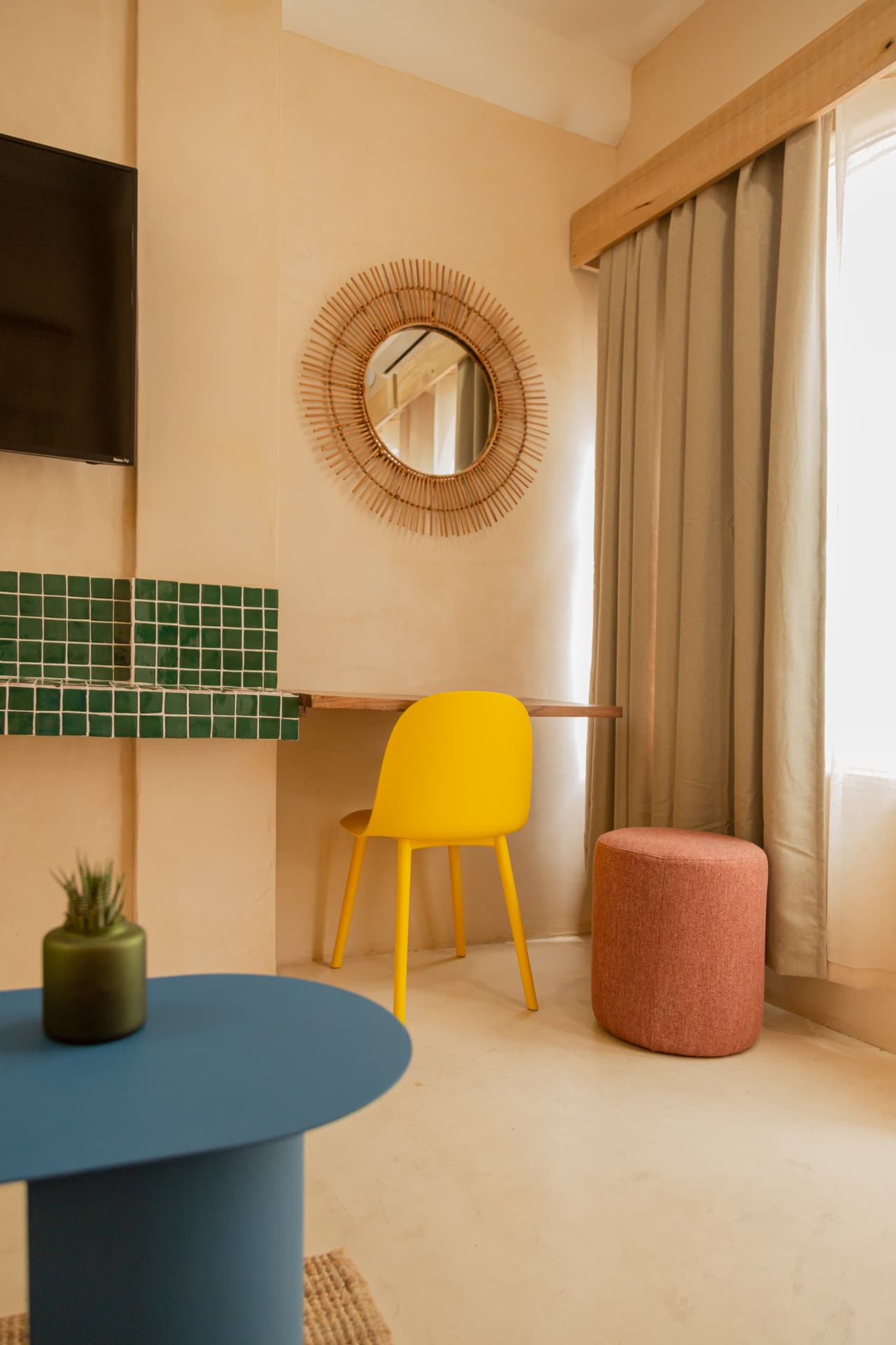 Desk by the window of Amaca Residence with green mosaics and yellow chair