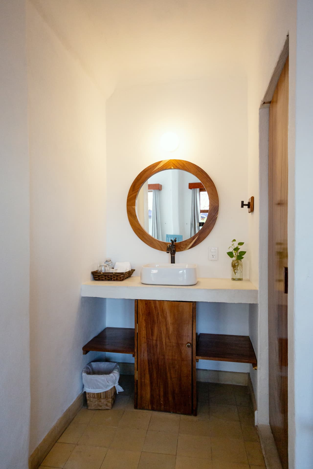 Vanity in Room 202 with round wooden mirror, wooden cabinet and shelf