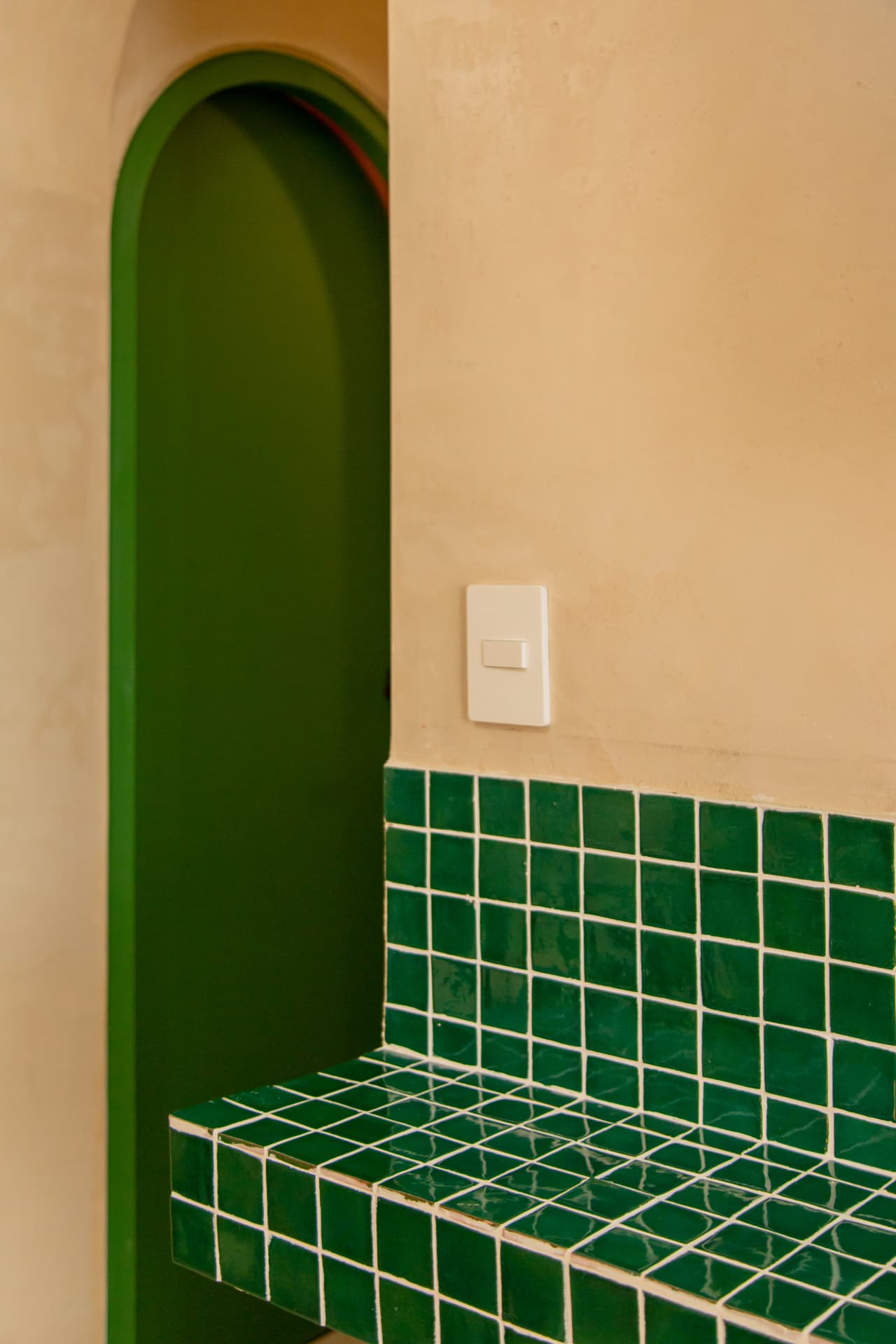 Detail of an arch and shelf with green mosaics in Amaca Residence