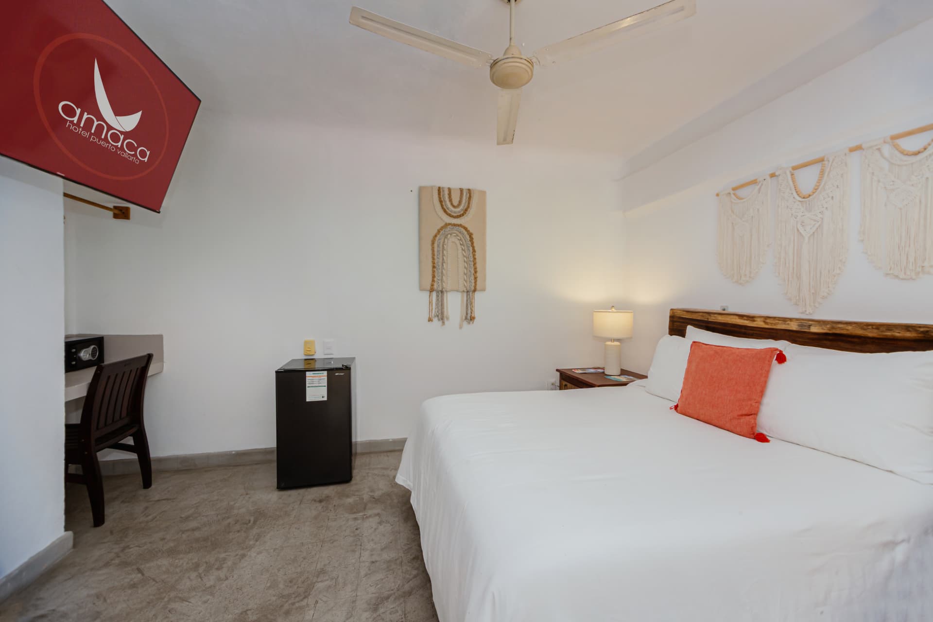 Vista amplia de la habitación 307 con cama Queen, escritorio, frigobar y TV con logo de Amaca